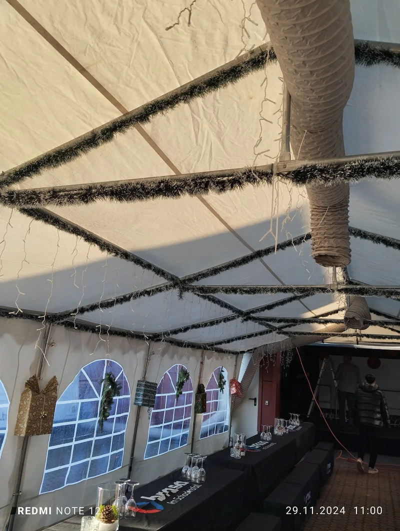 Weihnachtlich dekoriertes Zelt mit Girlanden und vorbereiteten Tischen