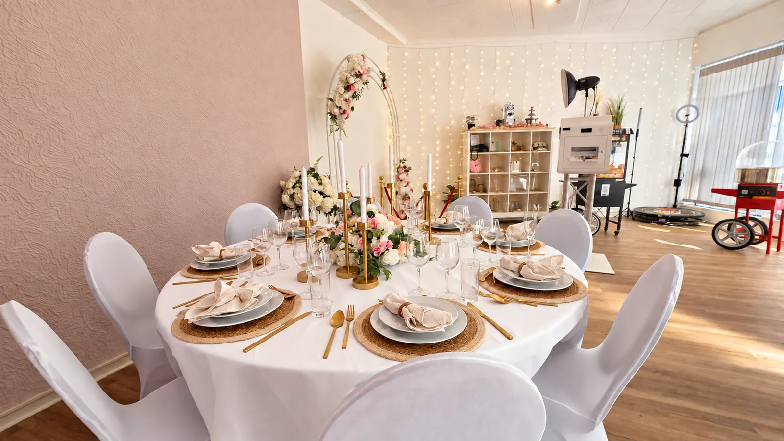Gedeckter Tisch mit Stühlen, Blumendekoration und Fotohintergrund im Rent-A-Party-Showroom